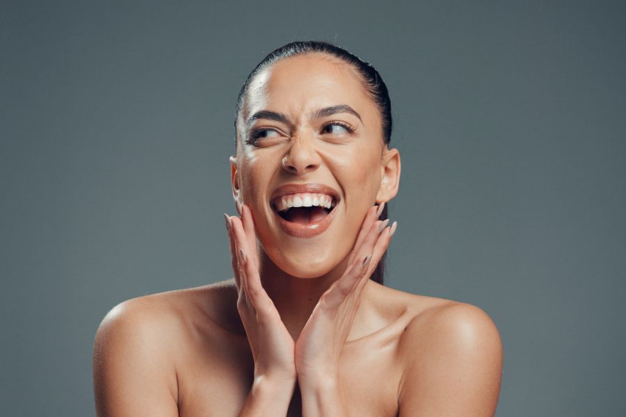 woman grins touching face